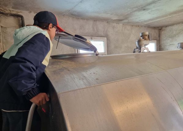 Un jeune regarde dans la citerne de lait