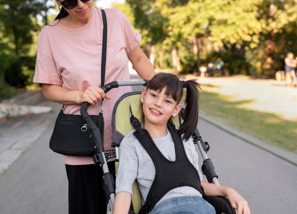 Une femme poussant et accompagnant une jeune enfant en fauteuil roulant dans une rue