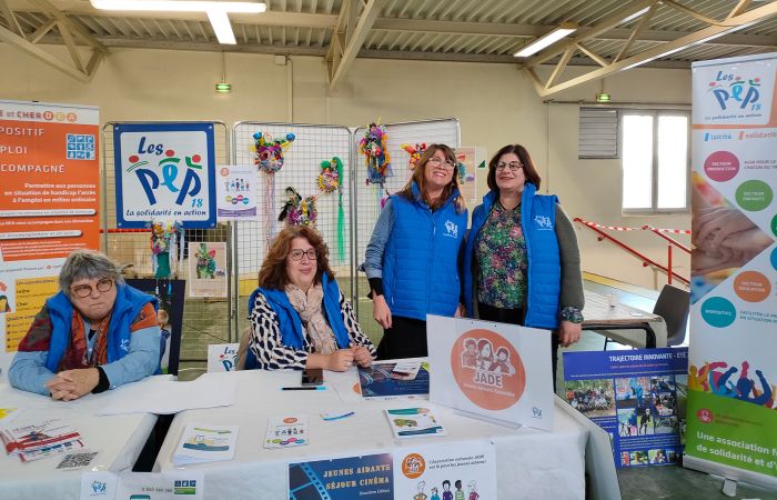 Groupe de Salariés et bénévoles de l'Asso PEP18 derrière une table / stand lors d'un salon dans le Cher pour promouvoir l'asso et ses missions