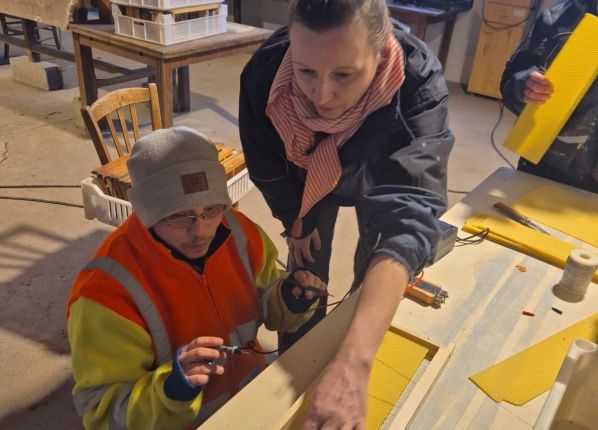 Monitrice dans un atelier de fabrication expliquant une consigne à un jeune en situation d'autisme