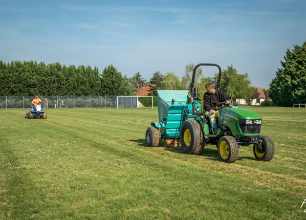 2 agents d'entretien d'espaces verts en train de tondre un terrain de foot
