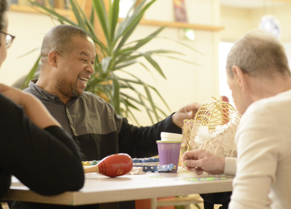 Un groupe d personnes âgés dans un centre pour adultes handicapés jouant au loto avec un animateur