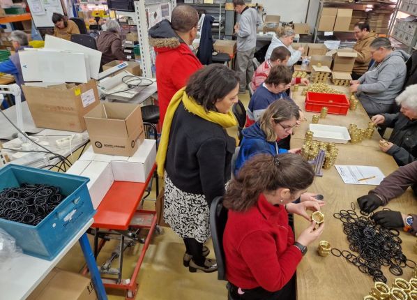 Groupe de travailleurs en situation de handicap, surveillé par des éducateurs dans un atelier de sous-traitance industrielle de l'EA de Vierzon